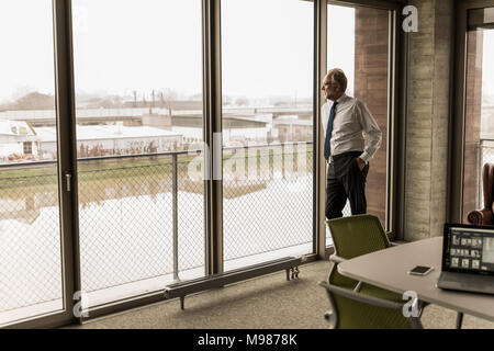 Schwere reifen Geschäftsmann stand am Fenster Stockfoto