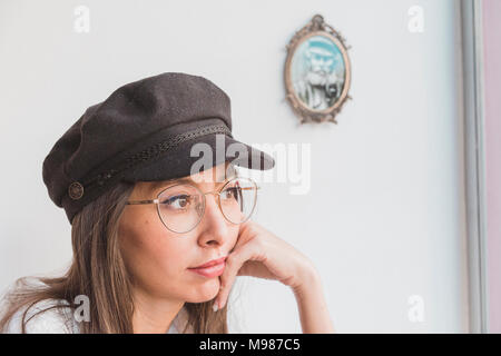 Stilvolle junge Frau Brille und Deckel denken Stockfoto