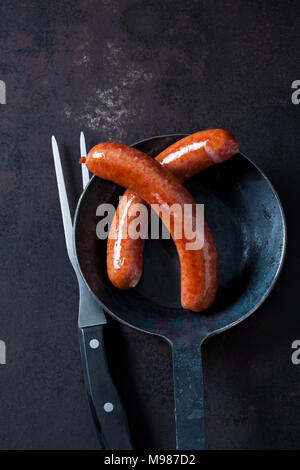 Zwei Hackfleisch Wurst aus Schweinefleisch in der Wanne und ein Fleisch Gabel auf rostiges Metall Stockfoto