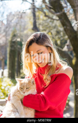 Glückliche junge Frau mit einer Katze in einem Garten Stockfoto
