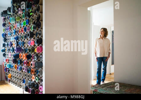 Reife Frau, die in einem Zimmer mit Auswahl an Yogamatten Stockfoto