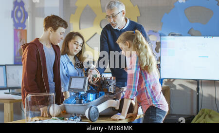 Lehrer und seine Schüler arbeiten an einem programmierbare Roboter mit LED-Beleuchtung für Schule Wissenschaft Klasse Projekt. Stockfoto