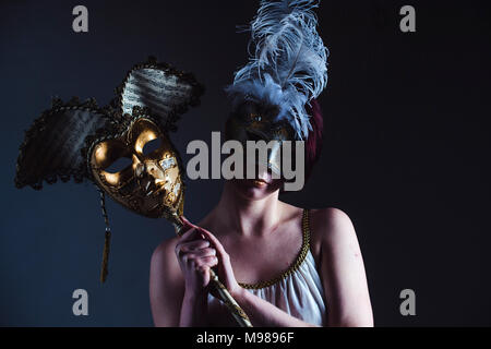 Halten Geheimnisse: eine Frau Mädchen mit einem aufwendigen Maskenball Maske, um ihre Identität zu verbergen, und halten ein weiteres Venezianische Maske Stockfoto