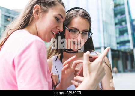 Zwei glückliche Mädchen im Teenageralter gemeinsame Nutzung Handy in der Stadt Stockfoto