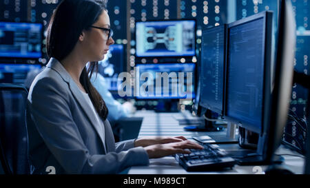 Ingenieurin Controller stellt die Arbeit des Systems. Im Hintergrund arbeiten und Monitore zeigen verschiedene Informationen. Stockfoto