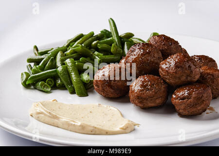 Gebratene Fleischbällchen und grüne Bohnen auf weiße Platte. Stockfoto