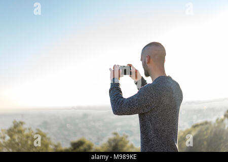 Junger Mann auf einem Hügel unter Handy Bild Stockfoto
