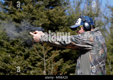 Ein Mann eine Pistole schiessen und die ausgeworfene Shell wird in der Luft sichtbar. Stockfoto