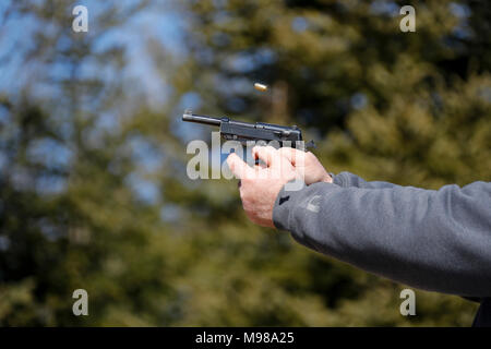 Nahaufnahme einer Pistole abgefeuert wurde und die ausgeworfene Shell wird in der Luft sichtbar. Stockfoto