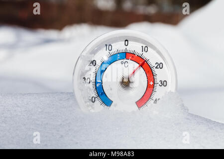 Thermometer with celsius scale in melting snow showing plus 13 degree temperature warm spring weather or global warming concept Stockfoto