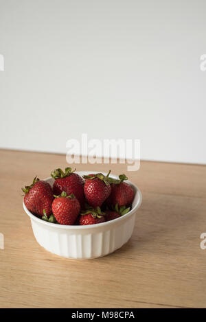 Erdbeeren in einem weißen Ramekin Schüssel auf eine leichte Backgrounf Stockfoto