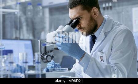 In einem modernen Labor Chief Research Scientist sucht in einem Mikroskop. Stockfoto