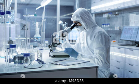 In einem sicheren Hohe Forschung Labor Wissenschaftler in einem Schutzanzug untersucht Petrischale unter dem Mikroskop. Stockfoto