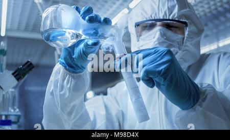 In einem sicheren Hohe Forschung Labor Wissenschaftler mischt Rauchen Verbindungen aus Tests Rohr mit Materie in einen Becher. Stockfoto