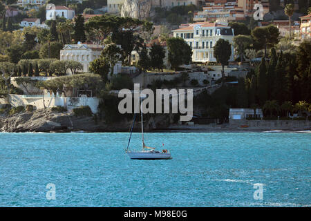 Segelboot mit dem Strand (La Plage du Buse) und die luxuriösen Häuser der Stadt von Roquebrune-Cap-Martin in den Hintergrund, die Französische Riviera Stockfoto