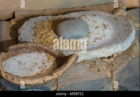 Jaen, Spanien - 29. Dezember 2017: Jungsteinzeit hand Mill Stone mit Gerste und Mehl Schale aus Kork. Selektive konzentrieren. Jaen Museum Stockfoto