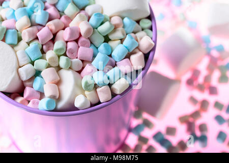 Violett Eimer mit verschiedenen Marshmallows auf einem rosa Hintergrund. Stockfoto