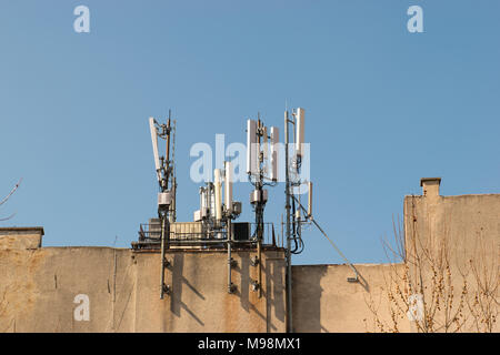 Handy Antenne auf dem Dach eines Gebäudes gegen den blauen Himmel. Rundfunk- und Netzwerk Kommunikatoren, Empfänger. Moderne Telefon und Kommunikation tech Stockfoto