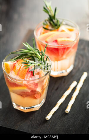 Zwei Gläser erfrischenden Drink mit Grapefruit und Rosmarin mit Strohhalm serviert. Stockfoto