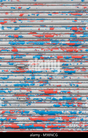 Zerschlagene geschlossen Rolltor mit abblätternder Farbe. Metapher geschlossen für Business, High Street Krise, leerstehende Geschäfte. Alte Farbe Textur, behindert.