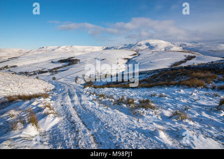 Wanderweg in der Nähe von Hayfield in den Hügeln des Peak District, Derbyshire. Ein schöner Wintermorgen. Die Hänge des Kinder Scout unter einer Schicht von Schnee. Stockfoto