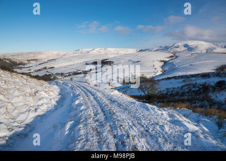 Wanderweg in der Nähe von Hayfield in den Hügeln des Peak District, Derbyshire. Ein schöner Wintermorgen. Die Hänge des Kinder Scout unter einer Schicht von Schnee. Stockfoto