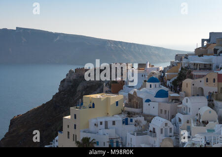 Stadt Oia auf Santorini Insel hoch oben auf den Klippen der Caldera mit der Insel von Therasia und das Meer im Hintergrund Stockfoto