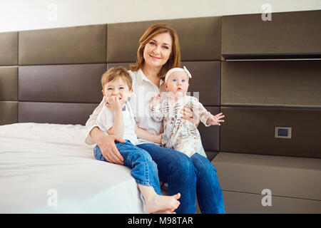 Großmutter mit Enkel sitzen auf dem Bett im Zimmer. Stockfoto