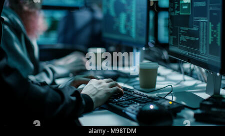 Nahaufnahme der Hacker mit der Tastatur. Es gibt Kaffee Tassen und Computerbildschirme mit verschiedenen Informationen. Stockfoto