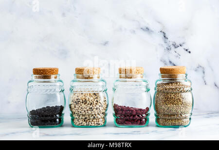 Verschiedene Arten von Hülsenfrüchten in Gläsern mit Kork Deckel auf einem Marmor Hintergrund Stockfoto