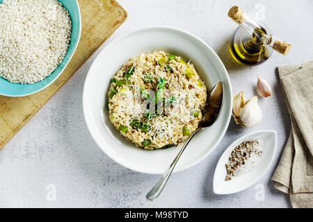 Italienische Risotto mit frischem Spargel und Parmesan in eine Platte und Zutaten auf einem Stein weiß Tisch Stockfoto