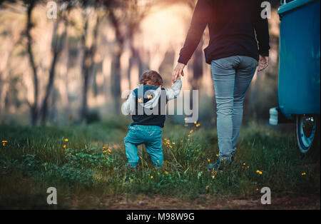 Mutter mit kleinen Sohn zu Fuß in den Wald, Wochenende Camping auf dem Land, in der Familie Zeit miteinander zu verbringen, die Liebe und die Unterstützung der Familie conc Stockfoto