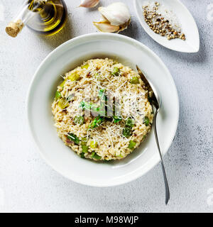 Italienische Risotto mit frischem Spargel und Parmesan in eine Platte und Zutaten auf einem Stein weiß Tisch Stockfoto