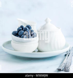 Das Frühstück am Morgen. Zuckerdose, Milchkännchen und Schüssel mit Blaubeeren Stockfoto