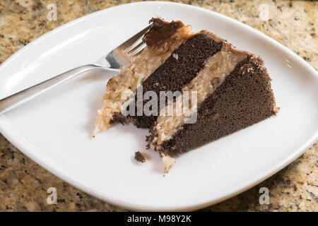 Stück deutscher Schokolade Kuchen auf einem weißen Teller mit der Gabel Stockfoto