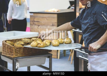 Baker fügt frisch gebackene Brötchen im Korb. Stockfoto