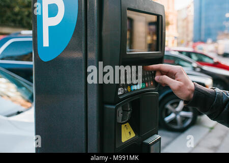 Hand ein unbekannter Mann Klicks auf die Schaltflächen der Parkplatz Maschine in Europäische Stadt Stockfoto