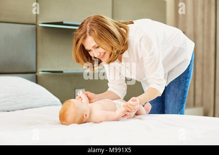 Eine glückliche Großmutter spielt mit Baby Enkel auf dem Bett im Zimmer. Stockfoto
