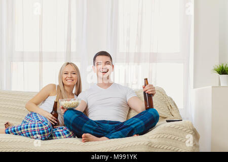 Paar funs mit Flasche Fernsehen sitzen auf einem Sofa im Zimmer auf. Stockfoto