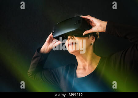 Eine ältere Frau in der virtuellen Realität Gläser. Eine ältere Person mit moderner Technologie. Stockfoto