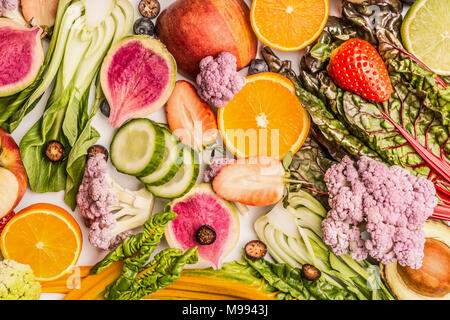 Buntes Obst und Gemüse Hintergrund mit der Hälfte der Orangen, Beeren, Ansicht von oben. Gesundes Essen und sauber essen Zutaten Konzept Stockfoto