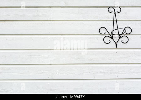 In der Nähe von weißen Holzplatte Wand- und Black Metal Blume Aufhängevorrichtung. Minimalistischer Stil. Stockfoto