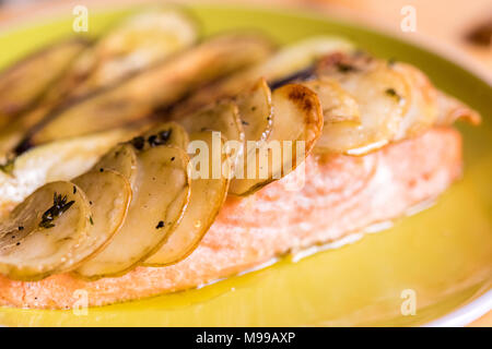 Lachs filet Steak im Ofen gebacken mit Salat und gebackene Kartoffeln in Scheiben geschnitten - auf der grünen Platte mit Jalapenos und Zitrone serviert. Stockfoto