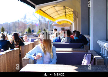 Schöne Mädchen an Street Café und trinkt Kaffee sitzen. Stockfoto