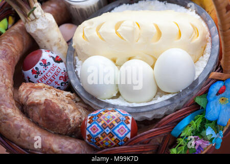 Stilvolle Ostern Korb mit Essen. Meerrettich, Butter, Wurst und bemalte Eier im Weidenkorb. Frohe Ostern. Stockfoto