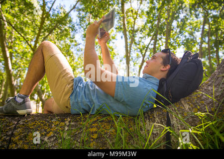 Mann liegen auf Baumstamm in der Natur unter selfie mit Tablet Stockfoto