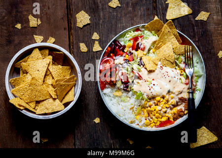 Taco Salat Schüssel mit Reis, Mais, Chili con Carne, Bohnen, Eisbergsalat, saure Sahne, Nacho Chips, Tomaten Stockfoto