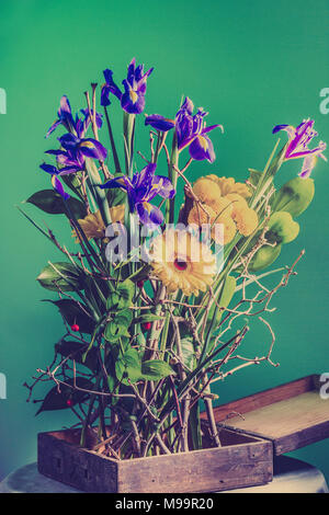 Einfache Holzkiste mit sehr hellen Schönen Blumenstrauß: Gerbera, dekorative Chrysantheme, Iris. Konzept für florale Grußkarte. Eco styl Stockfoto