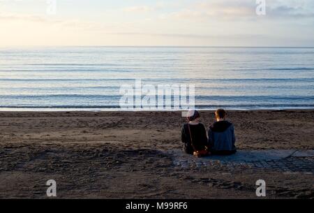 Ein Moment der Ruhe gemeinsam für ein junges Paar, das gemeinsam an der Strandpromenade Aberystwyth Februar 2013 Sitzung Stockfoto