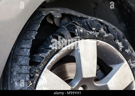 Close up Details einer Ausgeblasen Reifen mit explodierte, geschreddert und beschädigte Gummi auf modernem SUV Automobil. Flache flache Reifen auf einer Leichtmetallfelge, Rip Stockfoto